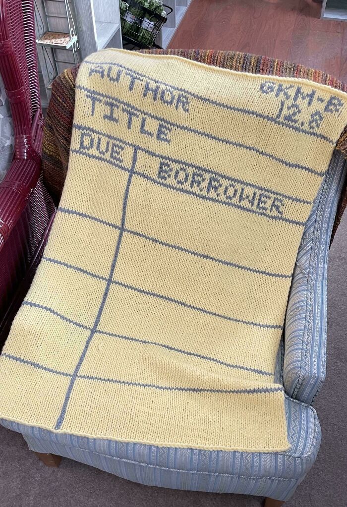 Knitted blanket resembling a library card, draped over a chair, showcasing a creative DIY project.