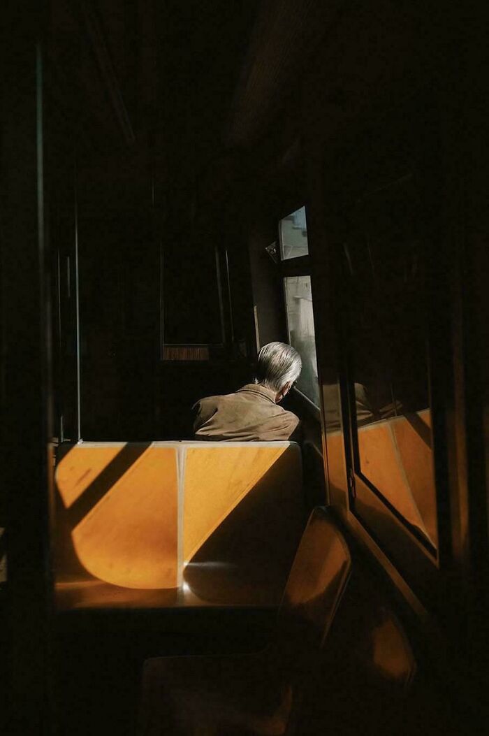 Man sitting alone on a dimly lit bus, evoking an accidental Renaissance painting feel.