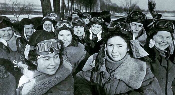 Group of women pilots in winter gear, smiling in a snowy setting; an interesting historical fact.