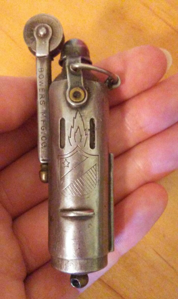 Hand holding a vintage metal lighter with engravings, showcasing Cool-Old-Things charm and intricate design.