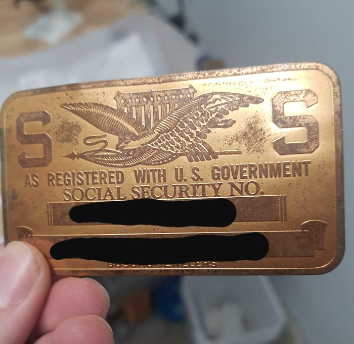 A vintage metal Social Security card with engraved details, representing cool-old-things.