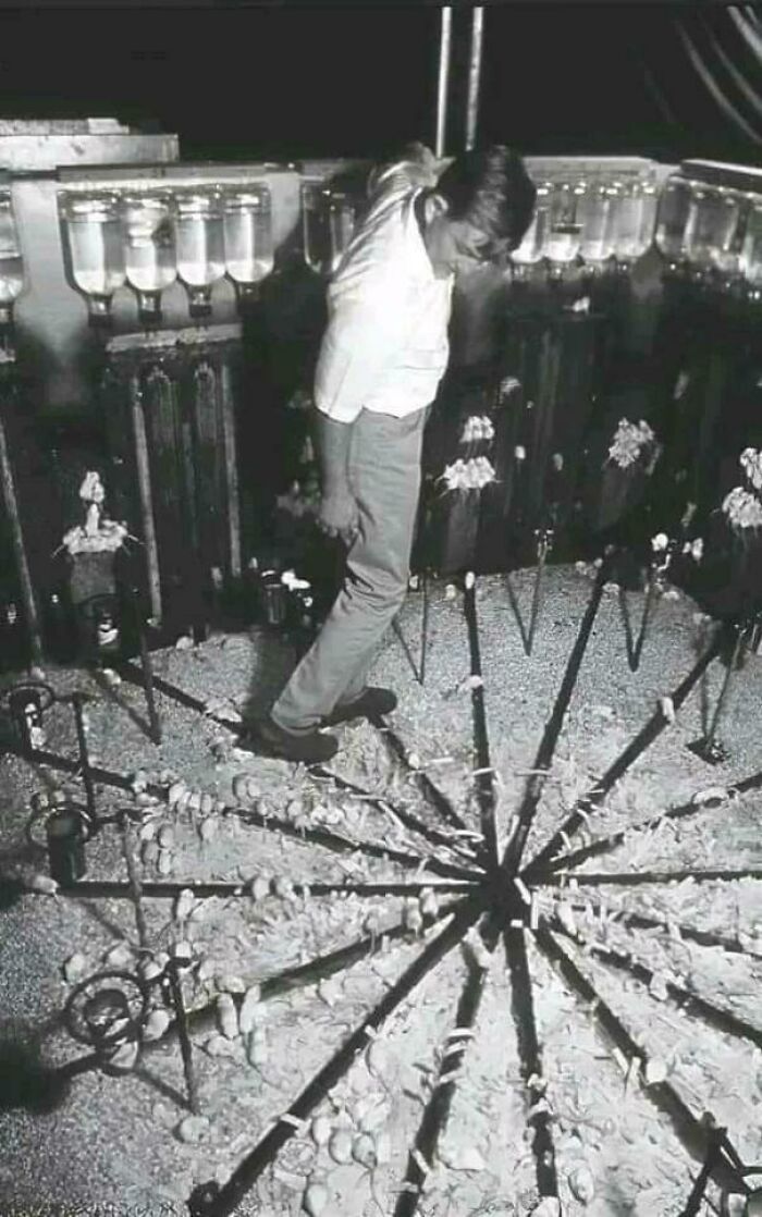 A man observing an interesting display of skewered items arranged in a circular pattern.