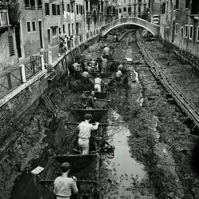 Workers cleaning a canal in Venice, highlighting interesting historical facts about urban maintenance practices.