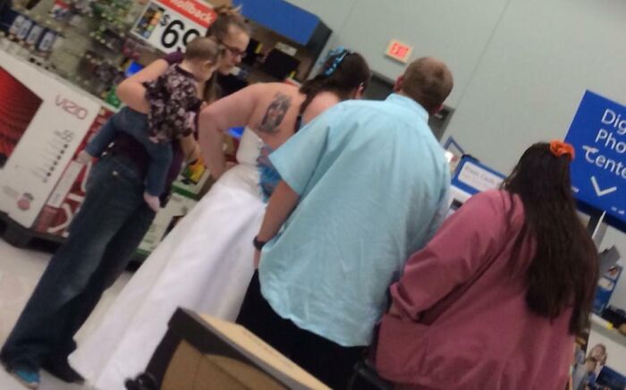 Bride in a white dress with a group inside a store, highlighting budget wedding fails.