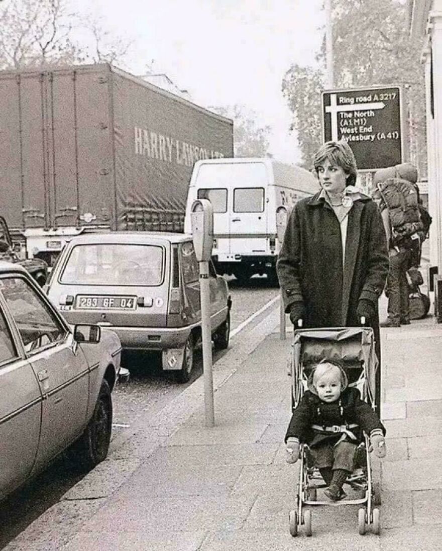 A woman pushes a child in a stroller on a busy street, showcasing historical life moments.