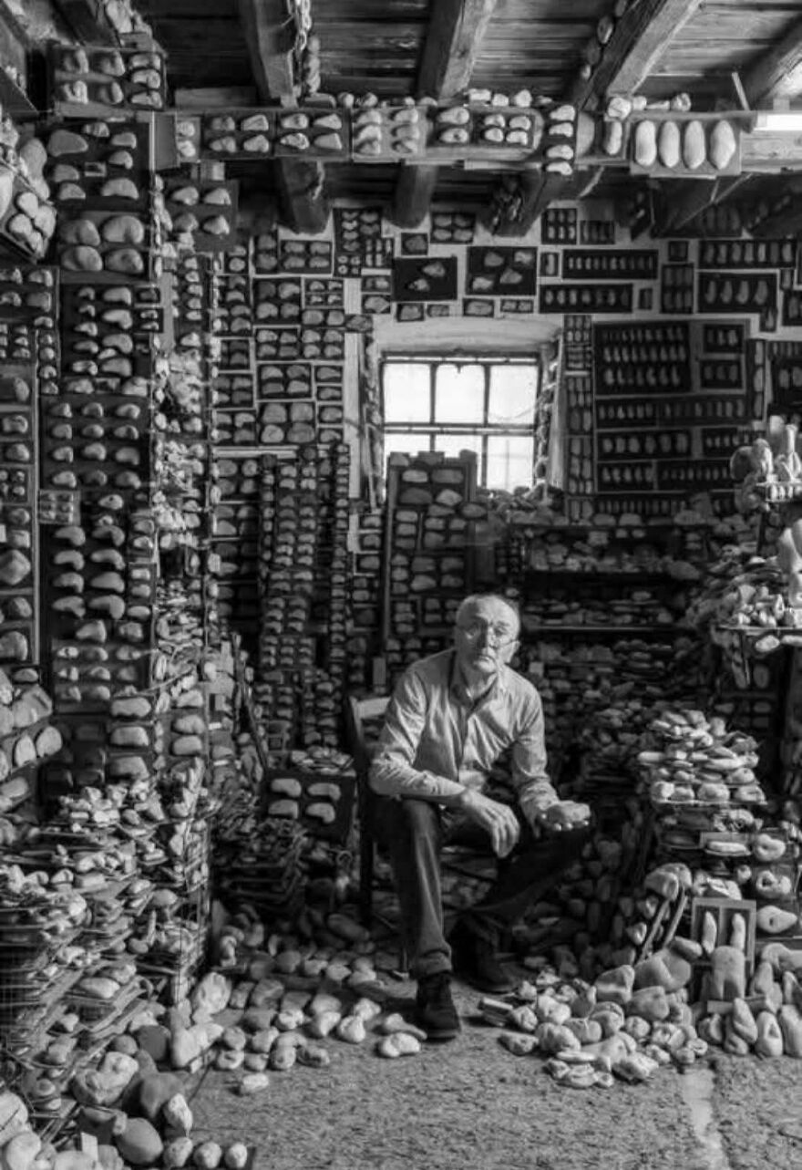 A man seated among shelves of historical artifacts in a dimly lit room.