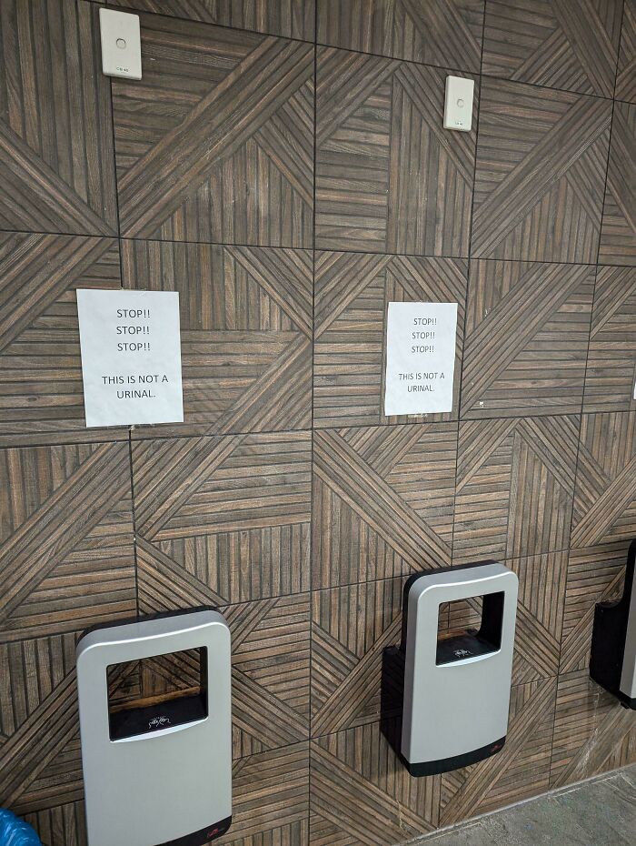 Funny signs on a wall saying "This is not a urinal" above hand dryers.