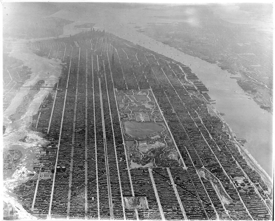 Aerial view of a historical New York City, showcasing Central Park and grid-like streets.