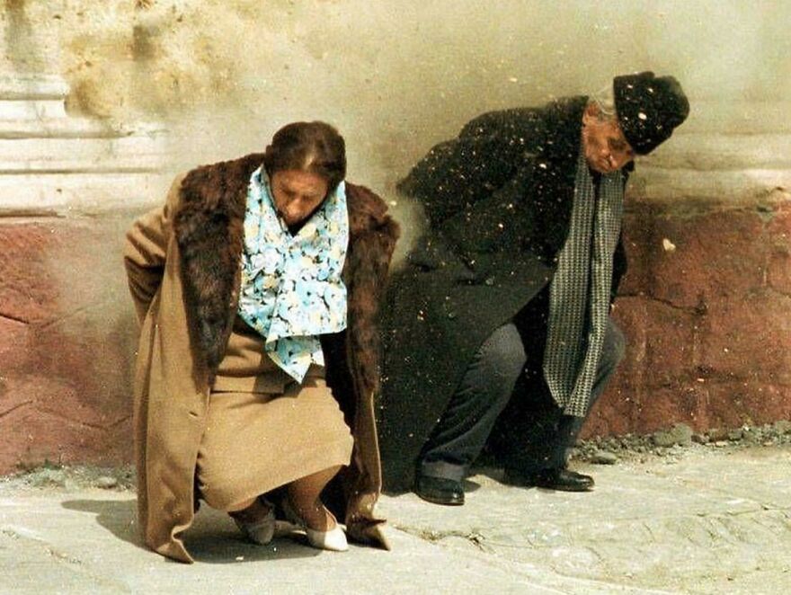 Two people standing against a wall, seemingly in distress, referencing historical photos.