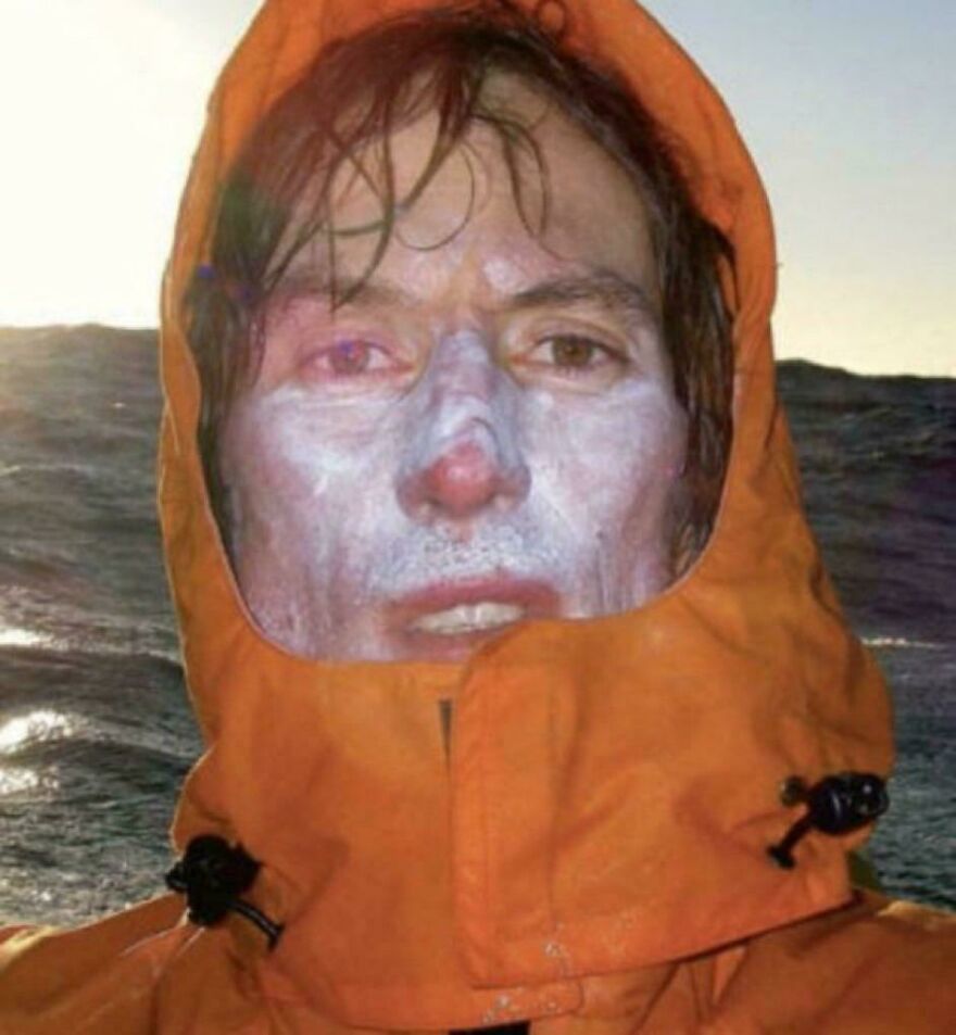 Person with white face paint in an orange hood, at sea. Historical photo capturing adventure essence.