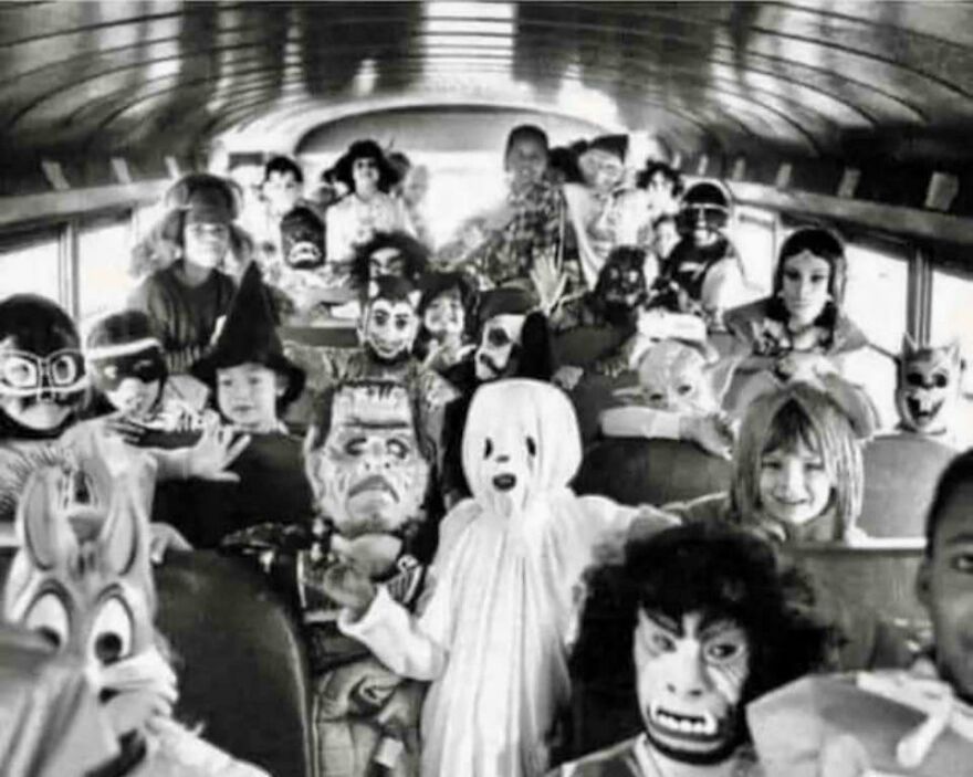Children in Halloween costumes on a school bus. Historical photo showcasing vintage masks and outfits.