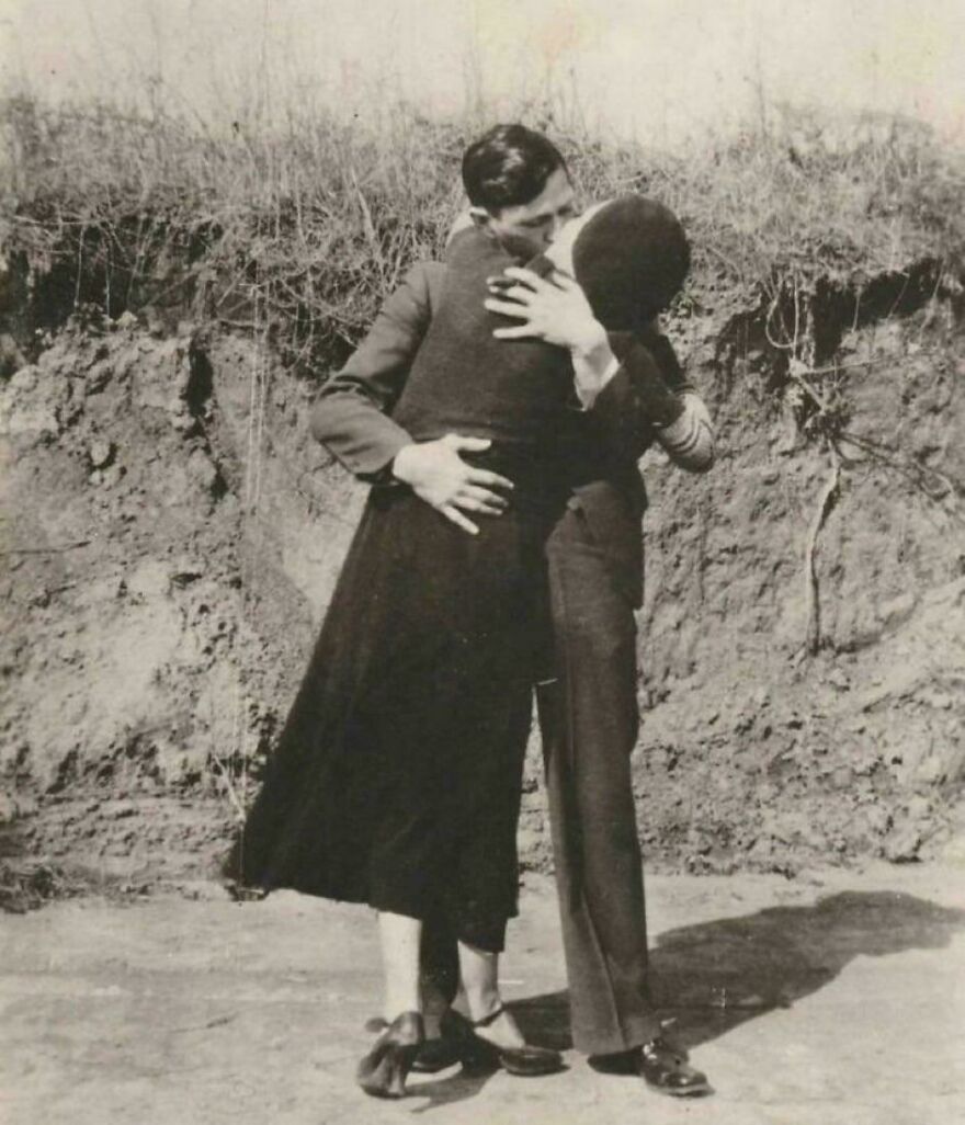 Historical photo of a couple embracing passionately outdoors, with earthy background and vintage attire.