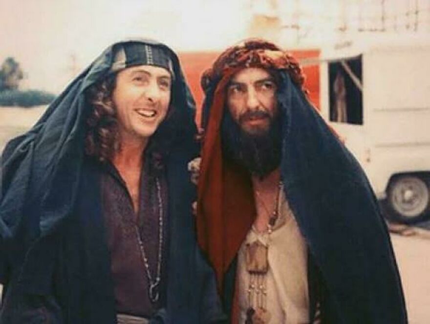 Actors in historical costumes with headscarves, smiling outdoors on a film set.