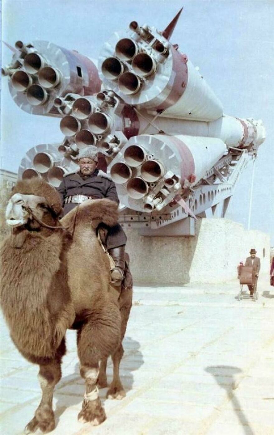 Man on camel in front of rocket engines, showcasing historical imagery.