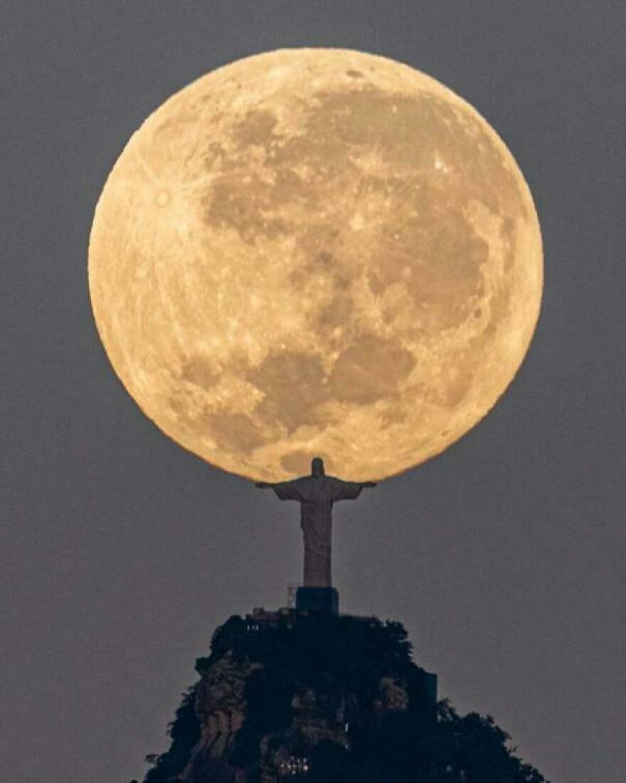 Historical photo of Christ the Redeemer statue silhouetted against a large full moon in the sky.