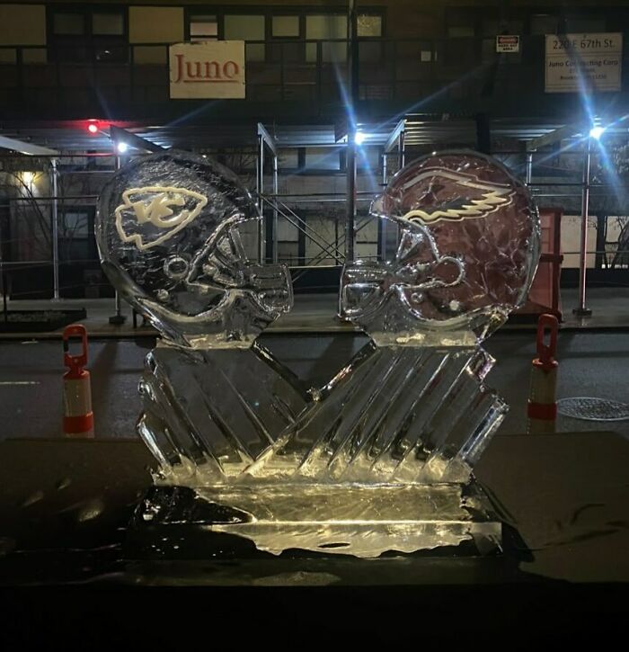 Ice sculpture of two helmets on a NYC street at night, reflecting the art of Stooping NYC.