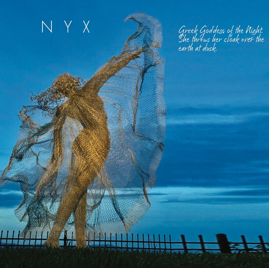 Chicken wire sculpture of a graceful figure with outstretched arms against a twilight sky.