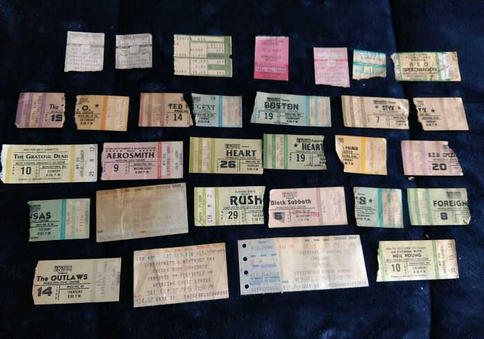 A collection of vintage concert tickets showcasing cool old things on a dark fabric background.