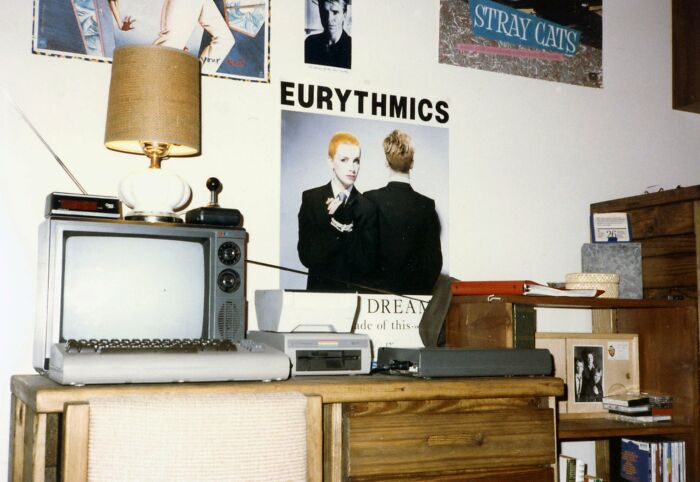 Cool-old-things in a retro room with vintage TV, lamp, posters, and cassette player on a wooden dresser.