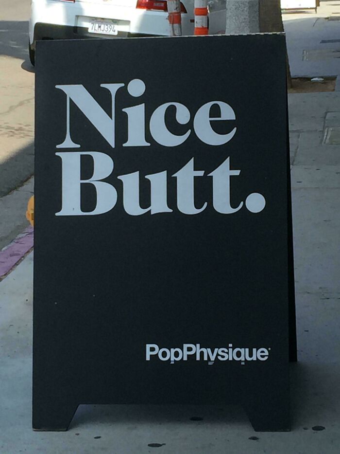 Funny sign with "Nice B**t." text promoting PopPhysique on a street.