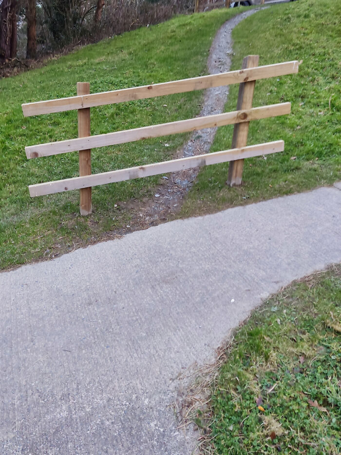 Wooden fence blocking concrete path with a visible dirt trail bypassing it, illustrating a perfectly preventable fail.
