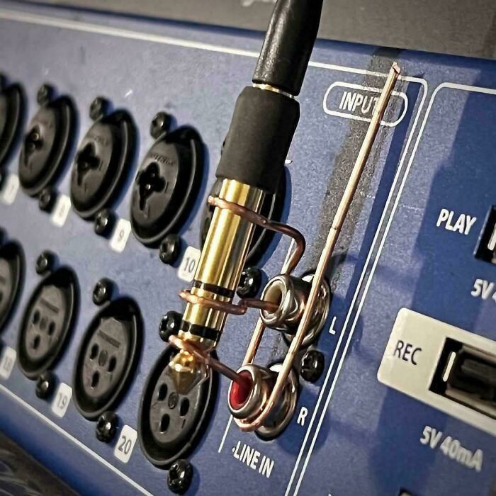 Close-up of a redneck engineer’s inventive cable holder on audio input ports showcasing ingenious creations that work effectively.