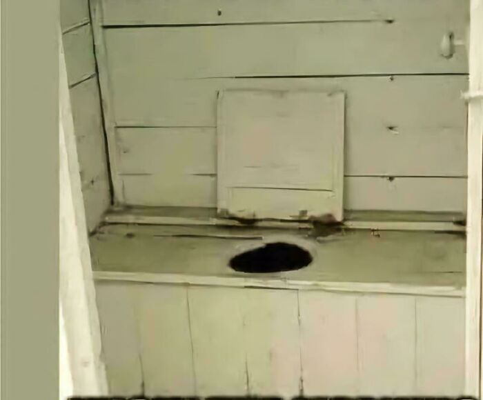 Antique wooden outhouse interior evoking nostalgic feelings of old ways.