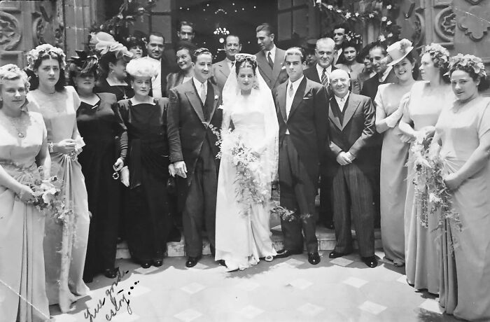 Black and white photo of a vintage wedding party with bride, groom, and guests in classic attire, a fascinating old image.