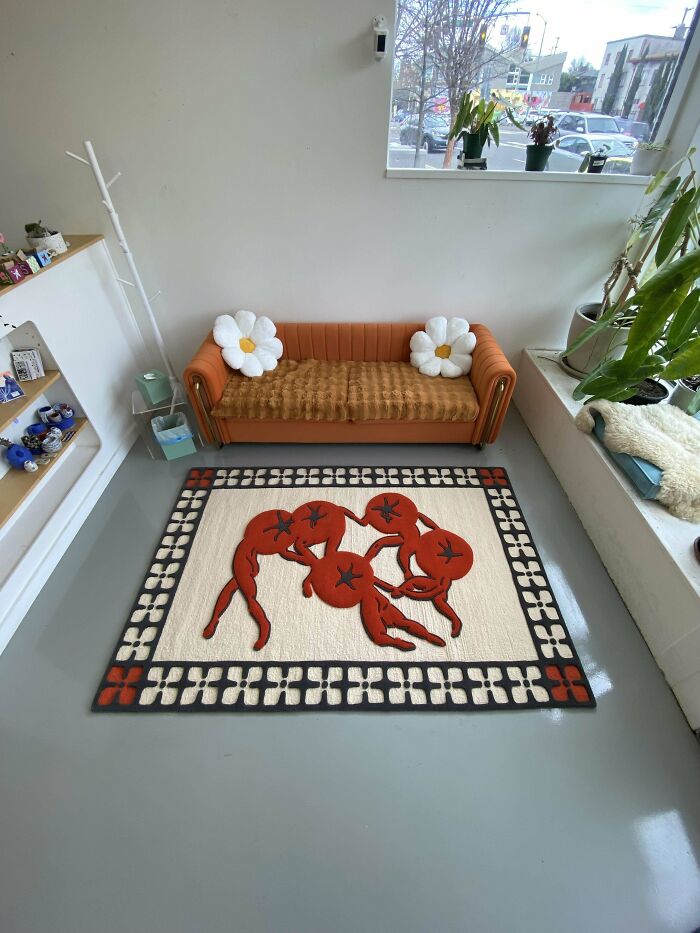 Unique DIY project featuring an artistic rug with red figures and a cozy orange couch with flower cushions in a bright room.