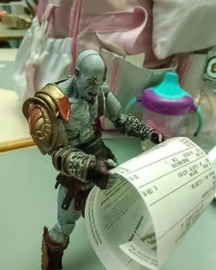 Figura de acción de Kratos revisando un recibo largo en una escena que provoca risas y diversión viral.