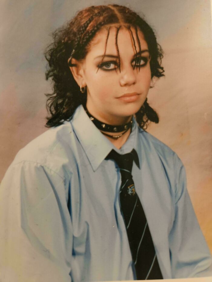 Teen with braided hair and heavy eyeliner wearing a blue shirt and tie, showing a regrettable past style from cringe-worthy pics.