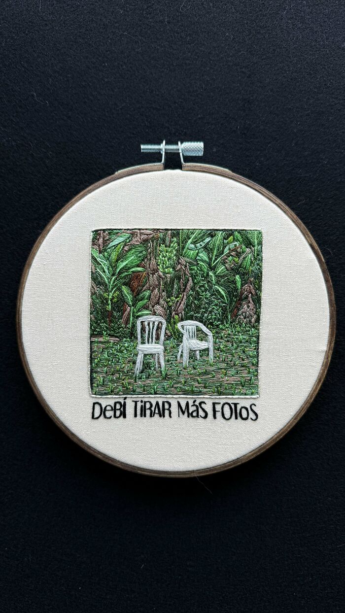 Embroidery hoop with detailed green foliage and two white chairs stitched, showcasing beautiful embroidery skills on beige fabric.