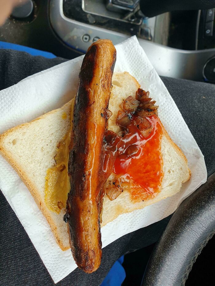 Australian sausage on white bread with grilled onions and sauces, representing unique local cuisine.