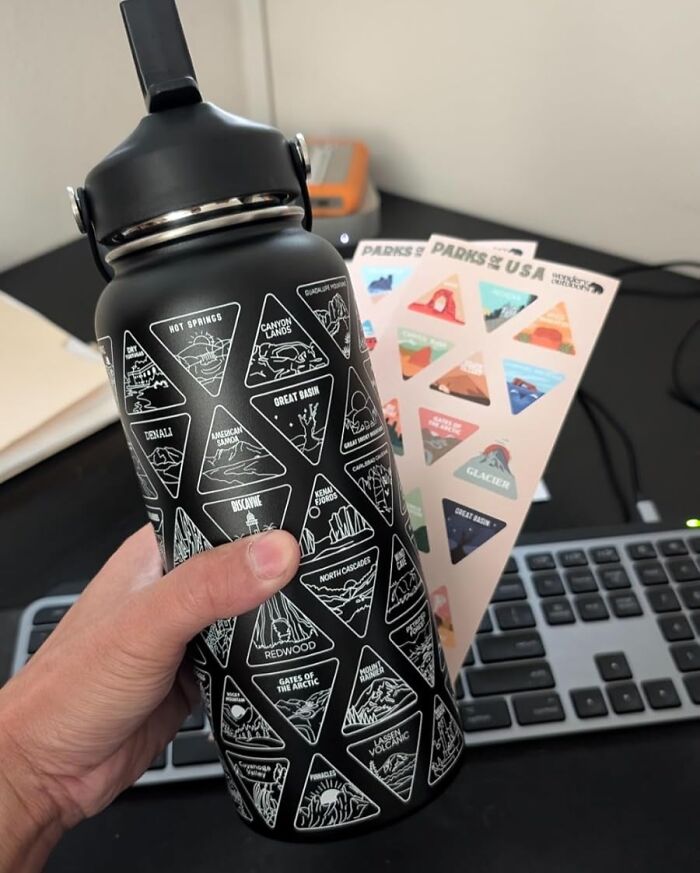 Water bottle with national park stickers held over a keyboard, a thoughtful V-Day gift for long-term couples exploring nature.