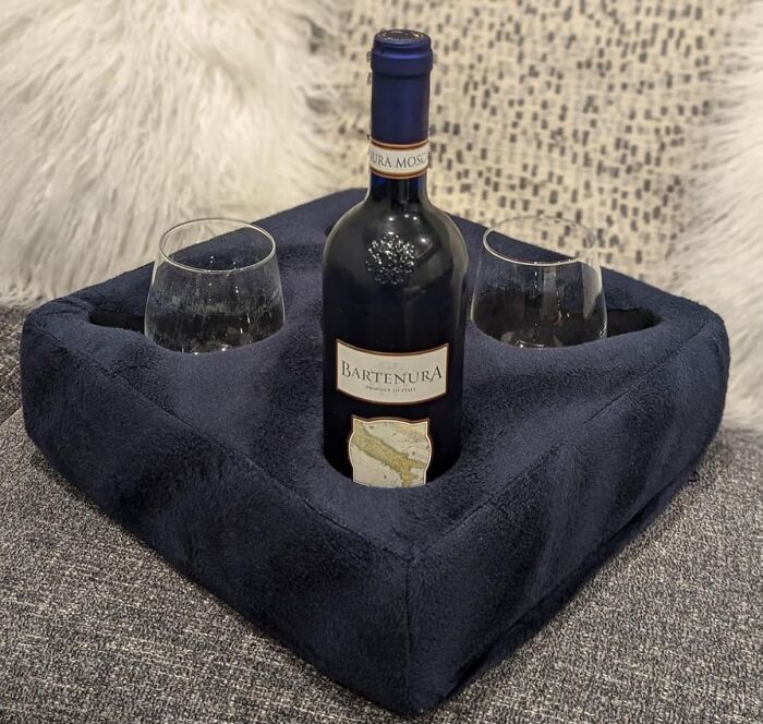 Wine bottle and glasses in a plush holder, perfect for V-Day for long-term couples, on a cozy couch setting.