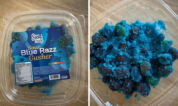 Sour Blue Razz Gusher candy, vibrant blue sugar coating in a clear container on a wooden surface.