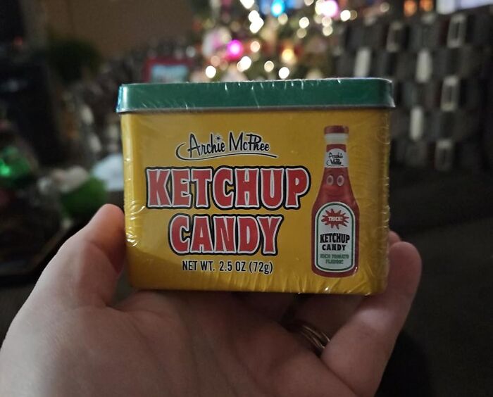 Hand holding a tin of ketchup candy, a unique snack that sounds wrong but might be so right.