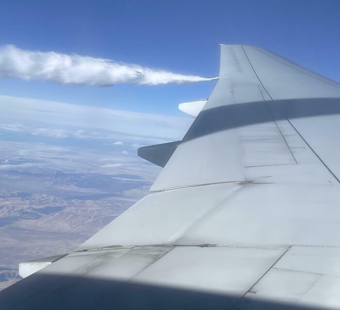 View from airplane window showing wing and cloud formation, creating a mildly interesting visual scene.
