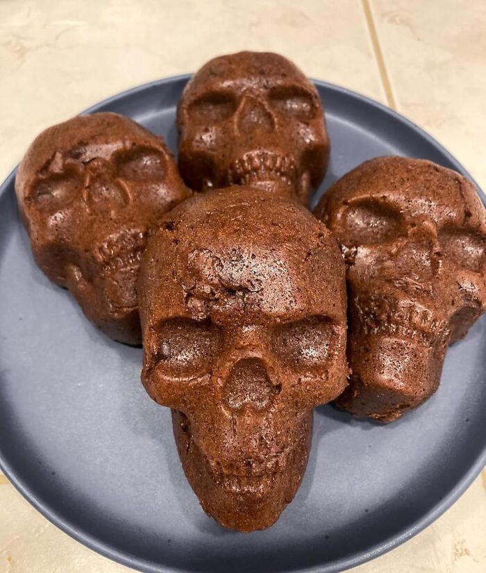 Chocolate skull-shaped baked goods on a plate, a tempting impulse buy worth the questionable financial decision.