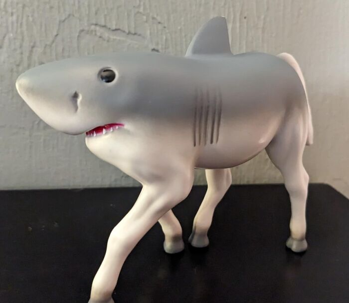 A playful figurine combining a shark's head with a horse's body, representing a whimsical impulse buy.
