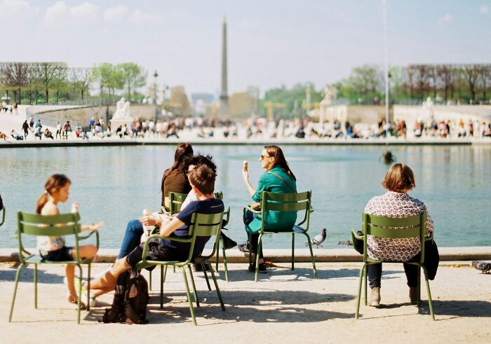 People relaxing by a pond, displaying cultural differences in leisure activities.