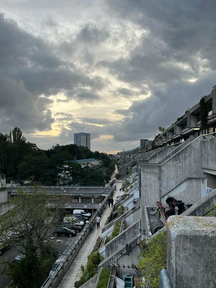 Urban hell scene with concrete buildings under a cloudy sky, evoking a dystopian atmosphere.
