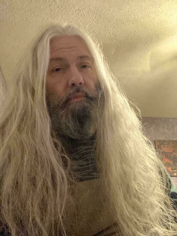 Man with long, flowing gray hair and beard indoors, showcasing fierceflow beautiful hair men style in soft lighting.