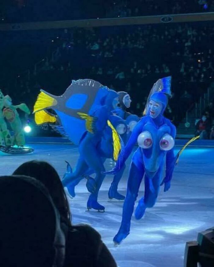 Performers in blue fish costumes with exaggerated eyes skating on ice in a show demonstrating awful taste but great e*******n.