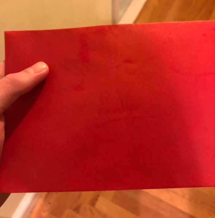 Red envelope held by hand on wooden floor, symbolizing Valentine's Day fails.