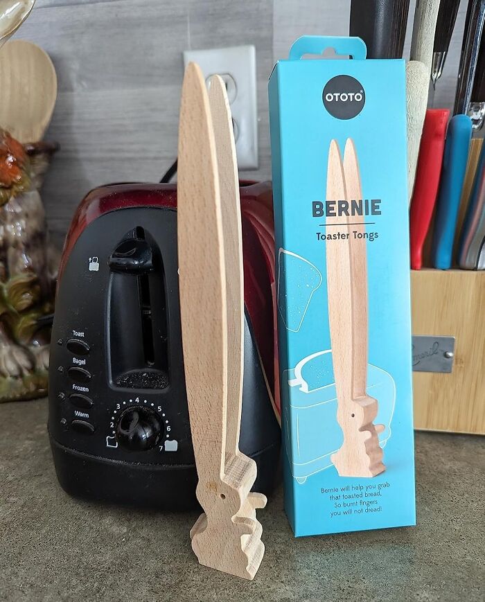 Wooden toaster tongs beside a toaster, showcasing a quirky kitchen item that performs surprisingly well.