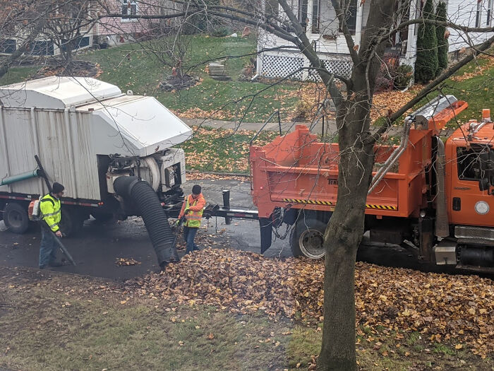 Workers using trucks and equipment to gather fall leaves, showcasing Cities-Genius-Solutions for urban cleanup.