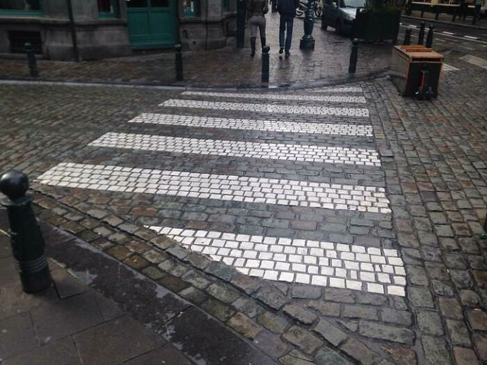 Creative crosswalk design on cobbled street illustrating Cities-Genius-Solutions.