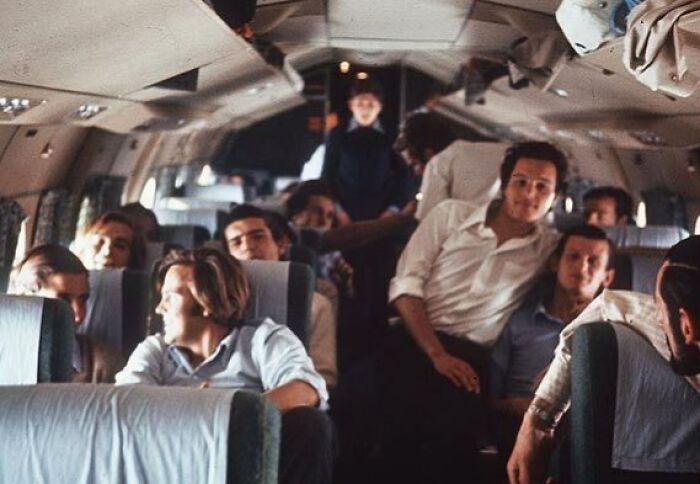 A group of people seated inside an airplane cabin, part of a photograph with a terrifying backstory.