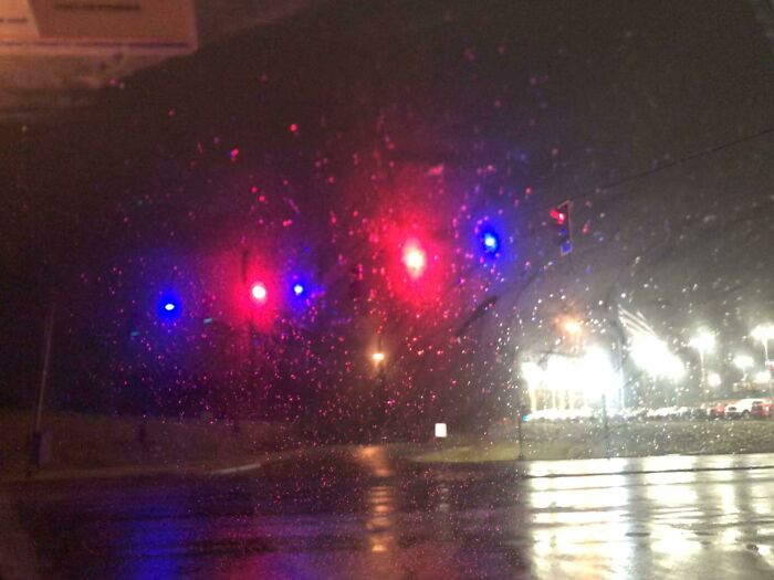 Rainy night street view with traffic lights showing through car windshield, illustrating Cities-Genius-Solutions.